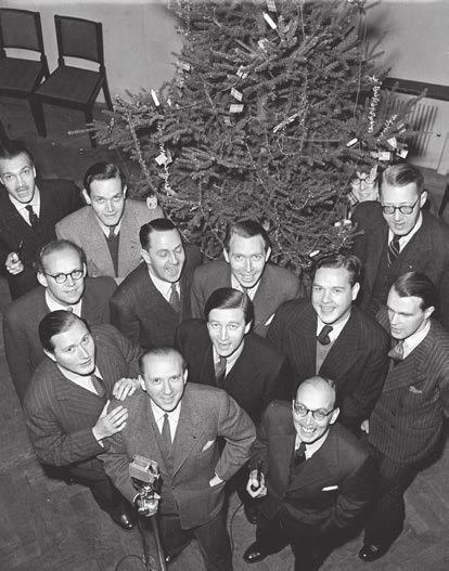 Hallåmännen julen 1943 samlade runt julgranen. Manne Berggren, med pipa i handen, och Sven Jerring på varsin sida om granen. Foto: Bertil Danielsson/TT.