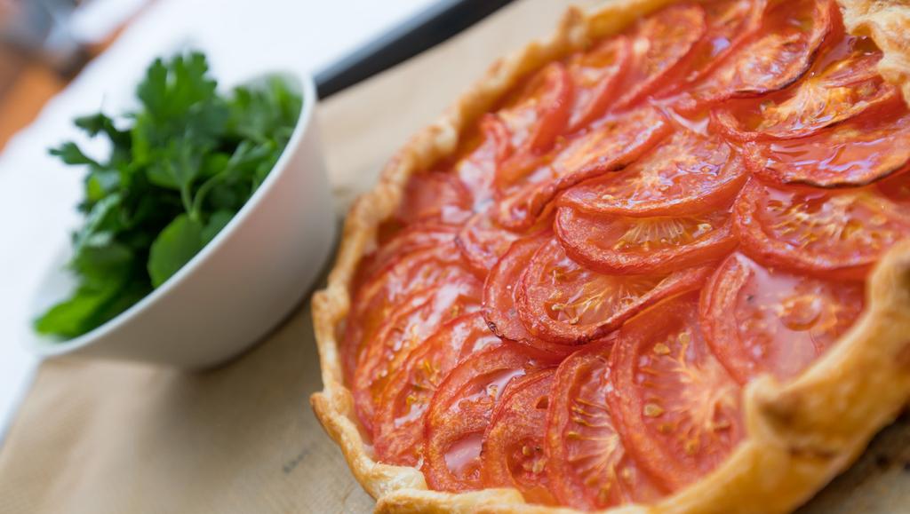 Tomatgalette med örtsallad 4 PORT 1 rund, kyld smördeg på rulle 4-6 svenska kvisttomater (antalet beror på tomaternas storlek) 1 ägg 3 krukor bladpersilja 3 krukor mynta 2 dl olivolja 2
