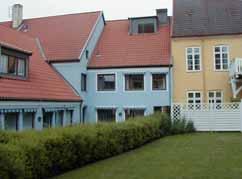 Ljusblå puts. Sadeltak, 1-kupigt rött tegel. Bruna hela fönster. Svart glasad stålramdörr. Vita fönsteromfattningar.