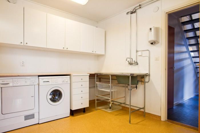 Tvättstuga Rymlig tvättstuga med plastmatta på golvet och vita väggar.