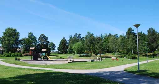 N Lekplats med klätterborg, gungbräda, sandlåda och trampkarusell.