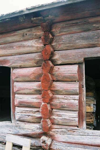 Något som ytterligare tyder på att knutarna är avkapade är att dragen mellan stockarna syns ute i knuten, vilket de inte gör vid AE-knut, jmf bild 12 och 13.