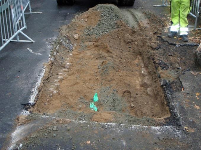 Fig. 6. Schaktet i Kung Valdemars väg, Notera den gamla lagda vägbanan som fanns intakt på ömse sidor om fjärrvärmeledningen som grävdes ned i gatan år 2013. Foto åt norr. Fig. 7.
