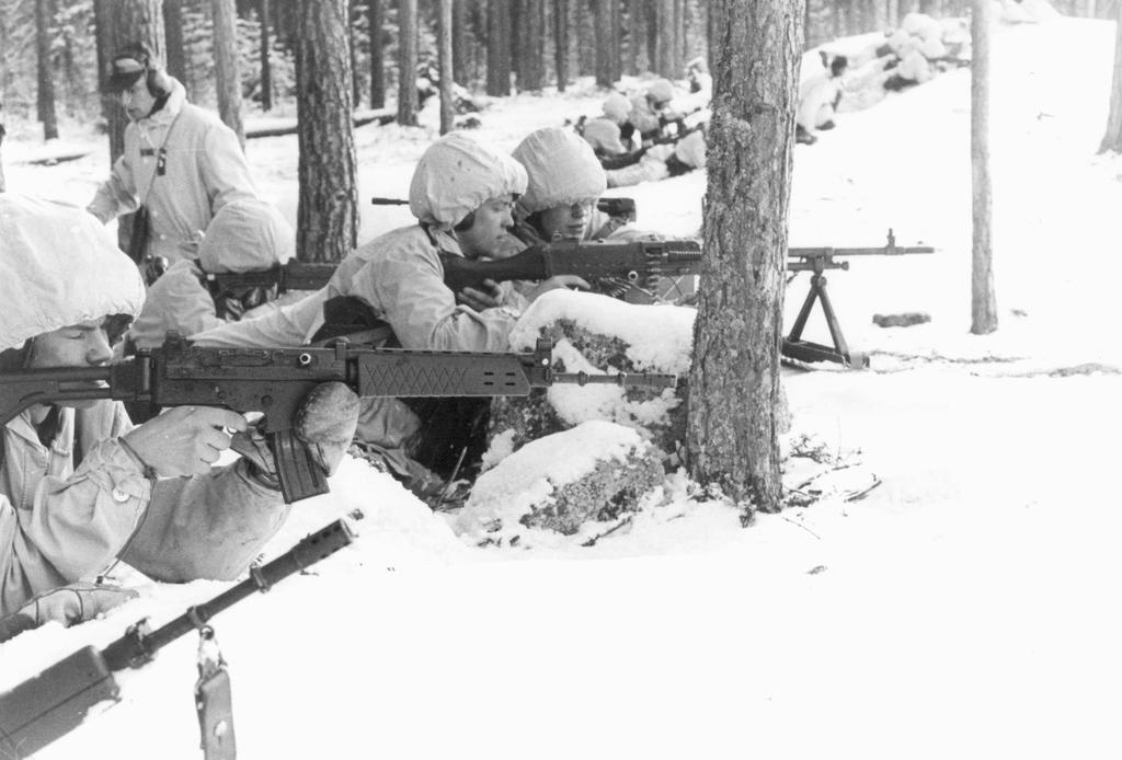 En skyttepluton gör eldöverfall i stridsställningen på Tjärnmyrberget norr om Hamréns kullar. Notera soldaternas bara skjuthänder.