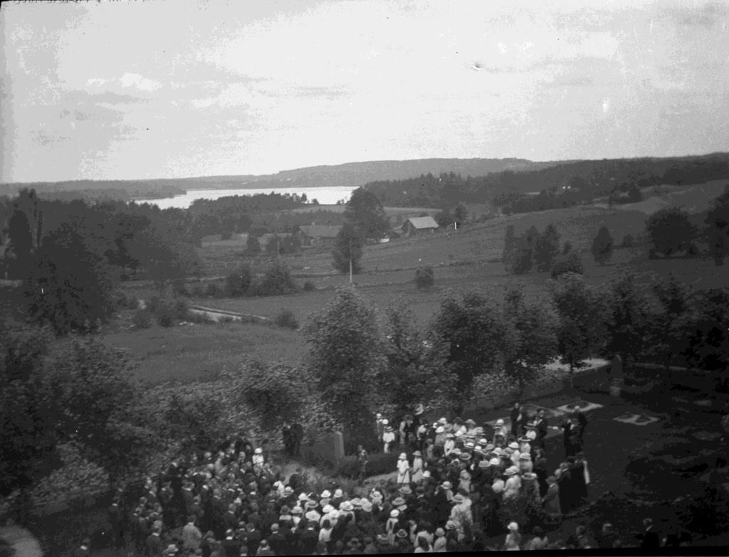 Från kyrktornet har man en vacker utsikt över stora delar av kyrkbyn och bort över Färgen. Den här bilden (93) är från 1920. Folket är samlat runt en öppen grav.