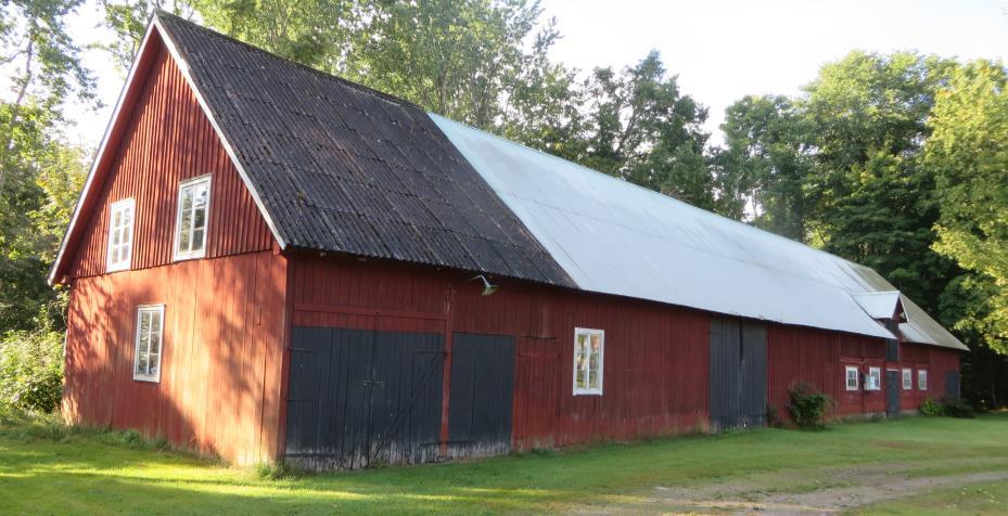 Gårdens ladugård (1939) i skiftesverk ligger idag öster om gården