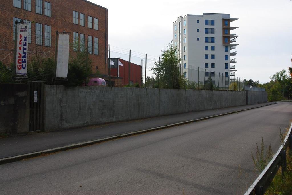 Muren begränsar det blivande bostadsområdet i öst mot vägen. Inget berg påträffas här. Till väster avgränsas området av älven Olidan.