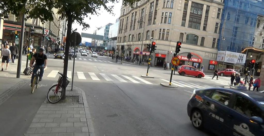 Figur 17 Bild från videoinspelning visandes konflikt som klassats som allvarlig. Fotgängare går mot rött till höger i bild. En olycka avvärjs genom inbromsning av den röda bilen.