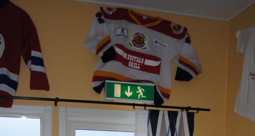 Längs väggarna står det flera vitrinskåp och det finns matchtröjor och vimplar upphängda på väggarna, se figur 2.5.