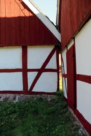 Till vänster den färdigrenoverade västra längans södra gavel med lagad vindskiva, vilken målats med vit linoljefärg.