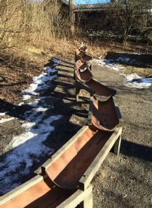 Räcket anpassas på delar av lekbron för att skapa lekfunktioner. Lekbron löper över bäcken på en nivå dit de höga vattennivåerna normalt inte når. Man ska ändå uppleva att man kommer nära vattnet.