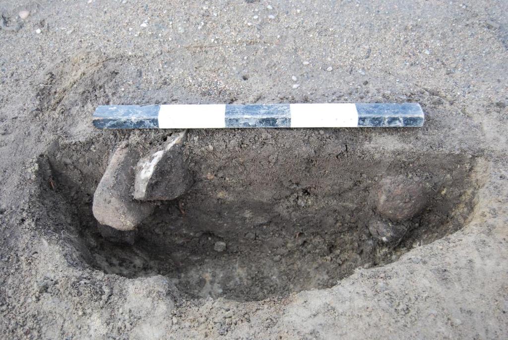 Litet runt stolphål med skarpt sluttande sidor och avrundad botten. Hålet hade följande mått: 26x24x25 cm och var fyllt med en mörkbrun/grå siltig sand och lite sten på under 5 cm.