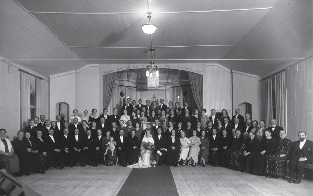 Gammalt bröllopsfoto som visar kyrksalen från tiden när kaminerna fortfarande fanns kvar. Strömslunds Missionsförsamling.