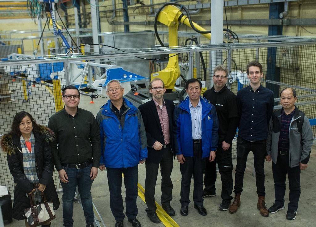 Delar av den kinesiska delegation från inspekterade produktionslinan i Sverige tillsammans med Absolicons personal och robotarna i produktionen.