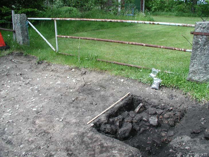 fornlämningen att avgränsa i alla riktningar, och att döma av sotiga spår i schaktkanterna är det sannolikt att den främst fortsätter mot N.
