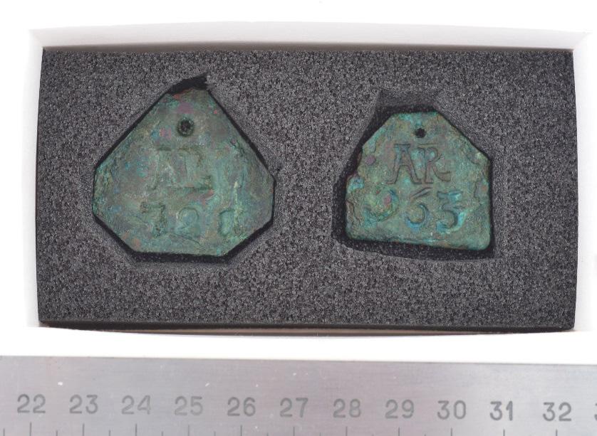 Arkeologgruppen AB rapport 016:39 Särskilda iakttagelser och analyser F 8 - Någon form av brickor för identifiering? Två hopkorroderade brickor (7/8-kantig och 6-kantig).