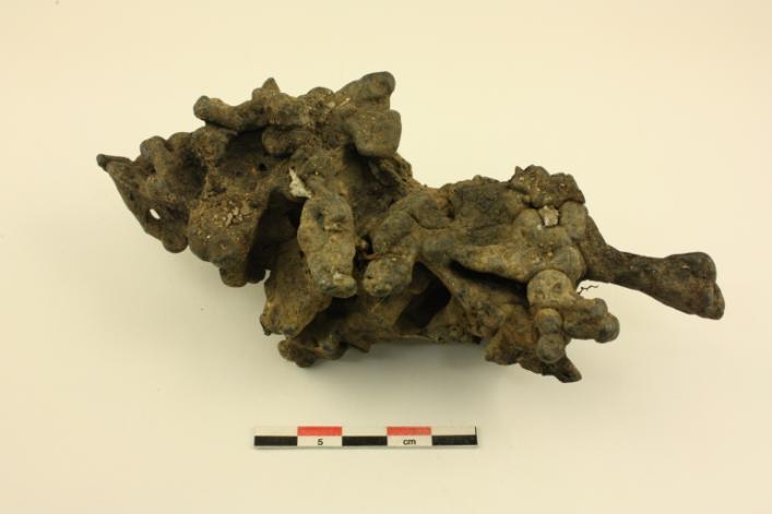 Undersidan där små fragment av bränd lera finns fastsmält. Avtryck efter kol kan också ses, men framträder tydligare i nästa figur. Figur 4.