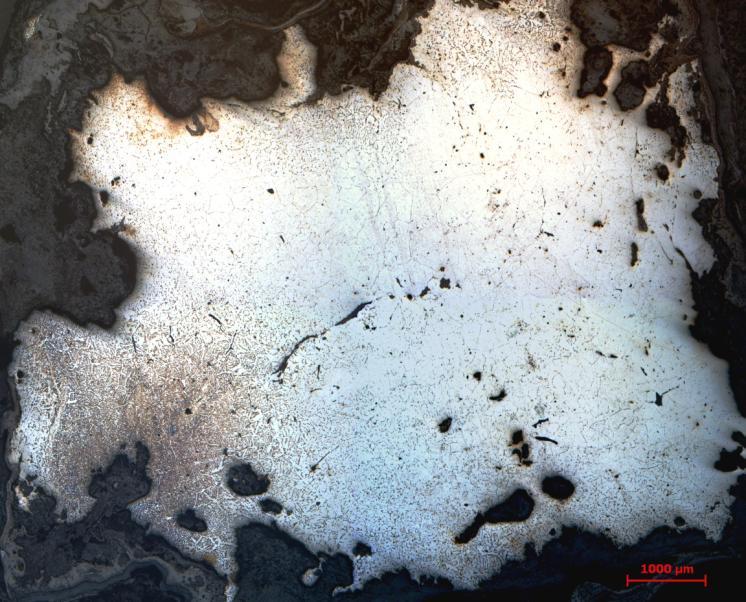 Figur 31. Det analyserade ämnesjärnet F157, undersökt i mikroskop på etsad metallyta. De tunna mörka stråken i metallen är slagginneslutningar. Den grå ytterkanten är mestadels rost.