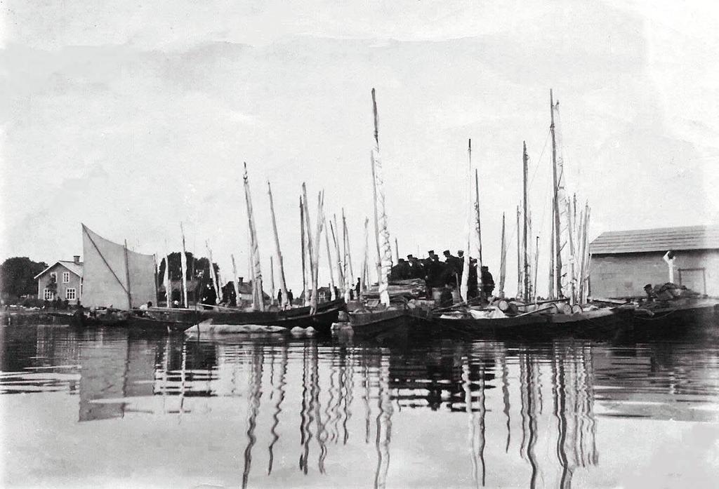 Skärgårdsbåtar i hamnen en marknadsdag omkring 1902. På kajen har en grupp människor samlats för att bedöma de medhavda kaggarna med saltad strömming.