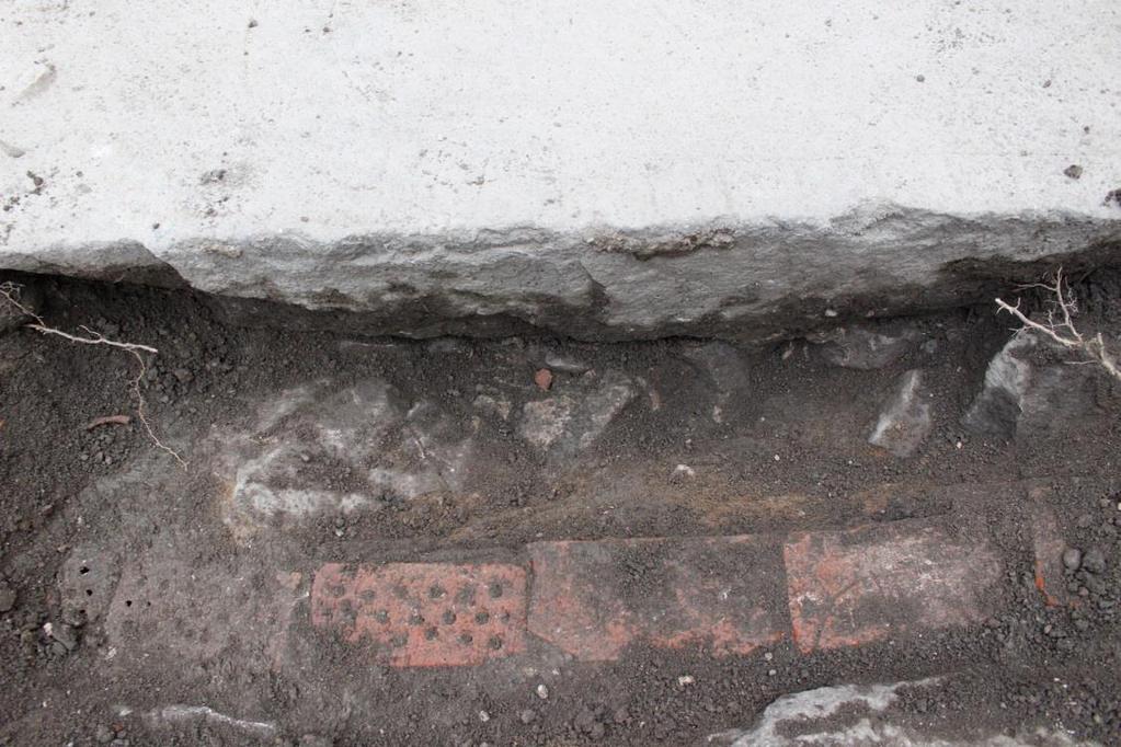 Figur 21. Detaljbild som visar fundamentstenarna på runstenens södra sida samt den elledning som grävts ned längs med stenen. Figur 22.