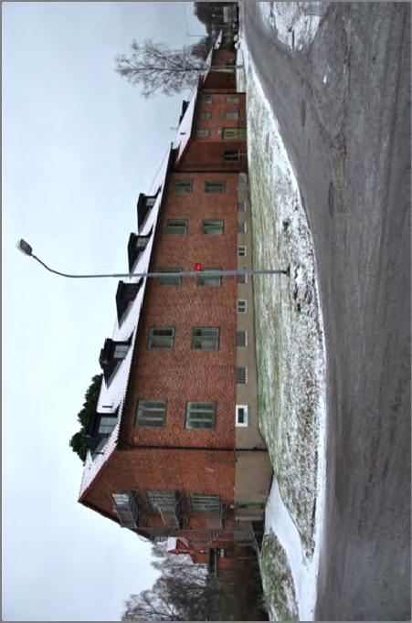 Kasernbyggnaden längst i söder. Alla tre byggnader är klädda med rött fasadtegel utan utsmyckningar med fönsteromfattningar och spröjs målat i en mörkgrön färg, och sadeltak med lertegel.