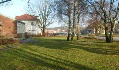 Bilden till vänster, södra sidan av Montessoriskolan högra delen av området som är avsett för utomhuslek. Bilden till höger visar fasaden mot Göteborgsvägen.