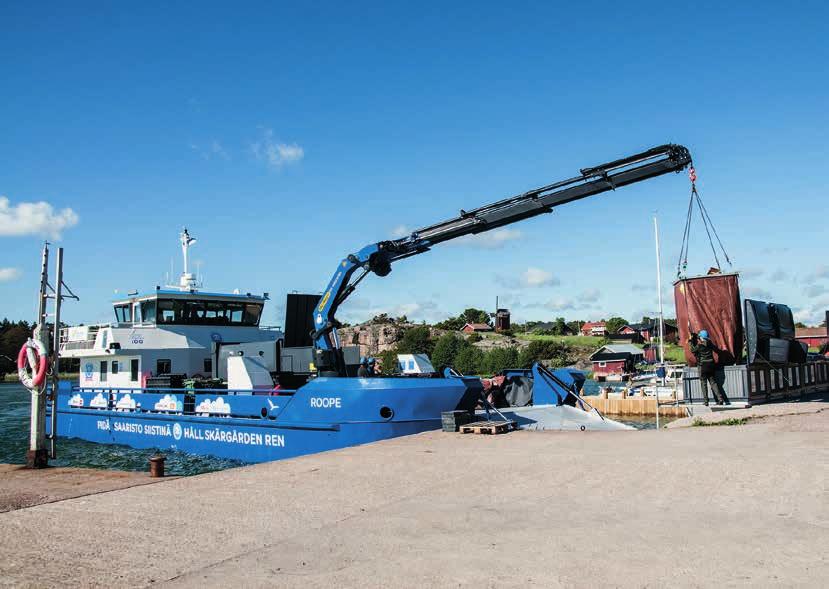 På Nötö tömmer man fyra fulla nedsänkta sopbehållare. Underjordsbehållarnas säckar lyfts dock lätt upp i luften med hjälp av den nya kranen, som kan flytta 1 000 kg från hela 20 meters avstånd.