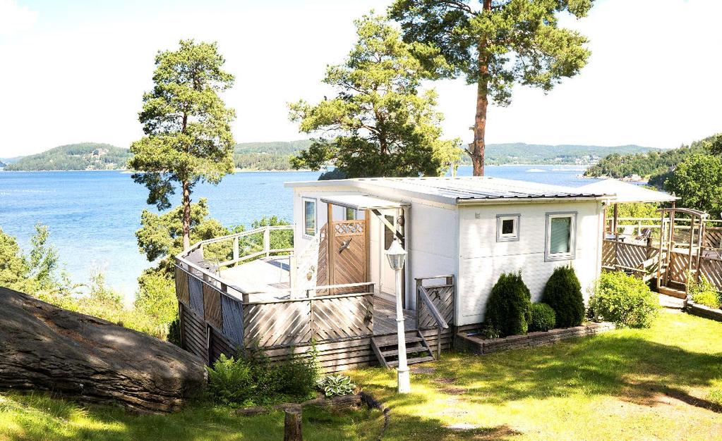 Örnnästet: A modern mobile home located on a cliff with a terrace facing the sea.