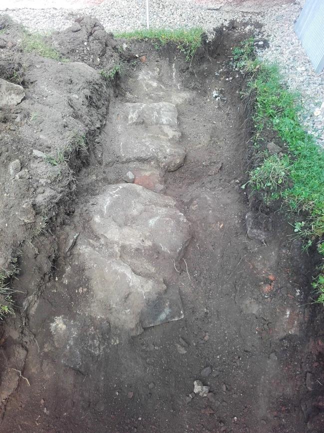 B Mur. Ca 1,5 m väster om Stureska gravkorets västra vägg påträffades resterna av en gråstensmur (figur 4, 9 och 10). Denna låg ca 0,1-0,2 m under mark.