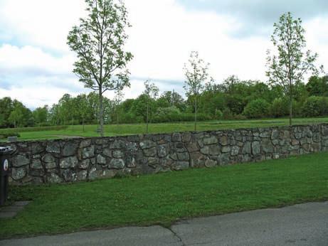 Omgärdningar En kallmurad stenmur av natursten och kluven sten inhägnar den äldre kyrkogårdsdelen. Muren är ca 1,5 meter bred och ungefär 1 meter hög.