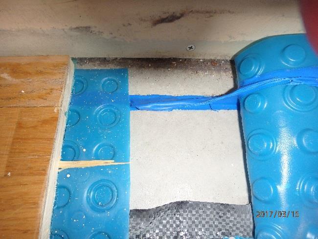 stegljudsdämpare. blå Platonmatta som vid kanterna ca 5 cm in från väggarna är förseglad med tätmassa mellan Platonmatta och betong. fiberduk i plast syns under Platonmatta ca 15 cm in från yttervägg.
