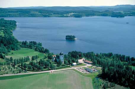 Fig. 12. Tuna kyrka ligger på en höjd ovanför en udde i sjön Marmen, omgiven av odlade områden med gårdar. Till kyrkomiljön hör prästgård och församlingshem, kyrkstallar och kyrkskola.