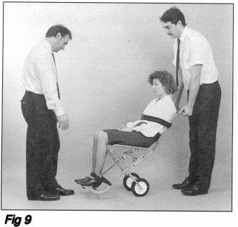 9 Den bakre personen fattar tag i ramen på stolen och lutar patienten/stolen bakåt tills vikten balanserar på hjulen. Stolen kan nu rullas utan att lyftas (se Fig. 9).