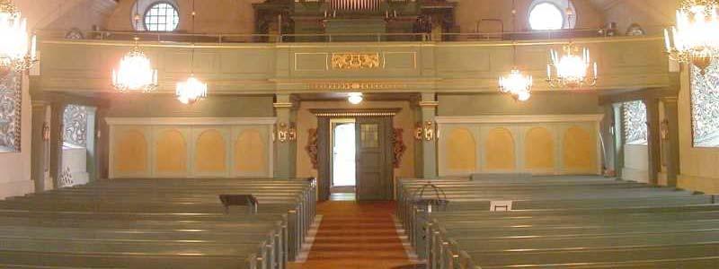 I korabsiden förändras färgskalan till guldskimrande, och ett förgyllt kors belyses bakifrån av en glasmålning med stiliserade blommor i en barockliknande altaruppsats.