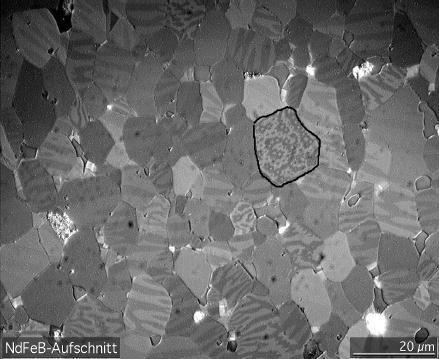 NdFeB under a Kerr-microscope showing magnetic domain structure. The material is composed of microscopic crystal grains. The domains are the light and dark stripes visible within each grain.
