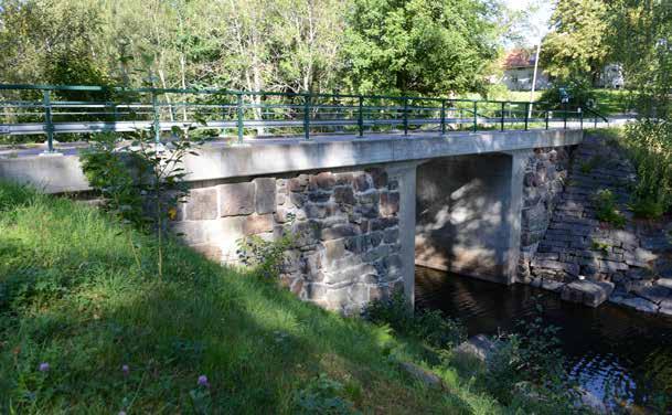17-178-1 Bro över Värmelns utlopp vid Borgviks kyrka En liten och i formen något udda plattrambro vars kantbalkar har dragits bakåt mot mötande bankar.