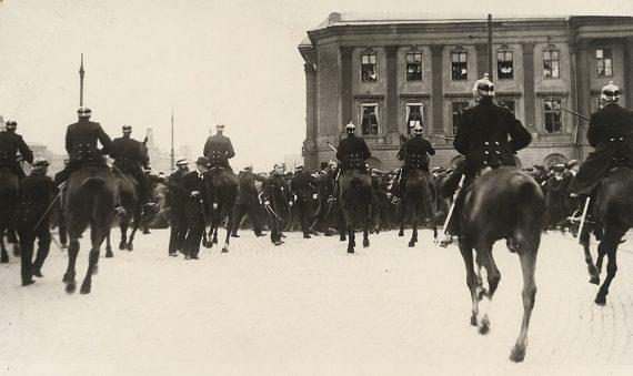 1 Anders Hagström Den svenska revolutionen Hjalmar Branting promenerar över Gustav Adolfs torg samtidigt som kravallpolis går till attack mot arbetare under en rösträttsdemonstration 5 juni 1917 Den