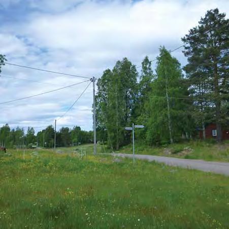 Väg 1044 anslutning mot befintlig väg 66 Väg 1044 norr om Rissätra gamla skola slingrar sig fram genom ett mosaiklandskap med åkermark, kuperad terräng och trädkronor som