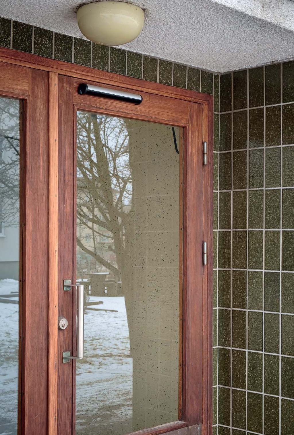 Tidstypisk entré med träpor, enkelt draghandtag, kakel som utsmyckning och