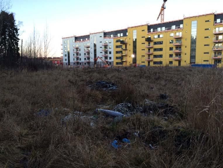 Till höger (utanför fotot) ligger en återvinningscentral. I fotot syns även den större arbetsvägen som sträcker sig genom hela området. Vid flaggorna ligger ett etableringsområde.