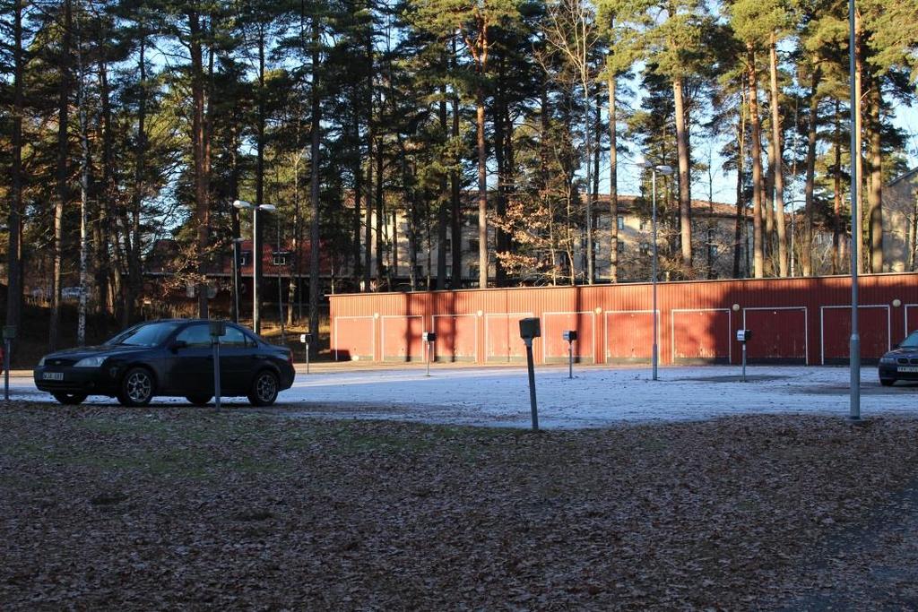 Foto på parkeringsplatsen samt parkeringshus i norra delen av utredningsområdet. Foto taget på platsbesök 2016-12-06.