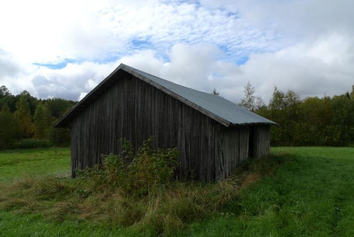 Objekt 11 Timmerlada med bilade stockar och spåntak (foto ovan t.h.). Taket är i dåligt skick. Ladan står i kanten mellan en vallåker och en grusväg.