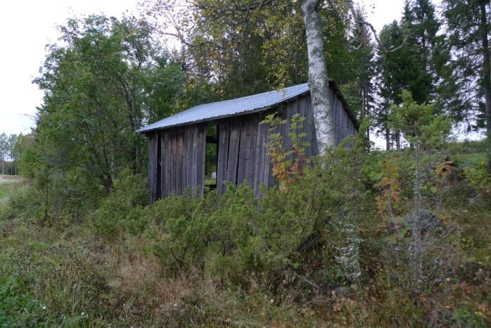 Objekt 17 Brädlada på en liten åkerholme omgärdad av sädesåker (foto ovan t.h.). Ladan har tak av pannplåt. På södra sidan växer sly som en vägg.