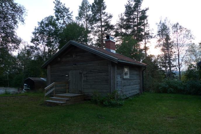 Vattlång, öster om Ilsbo Objekt 43 Brädlada med tak av pannplåt som står i kanten mellan en vallåker och en skog.