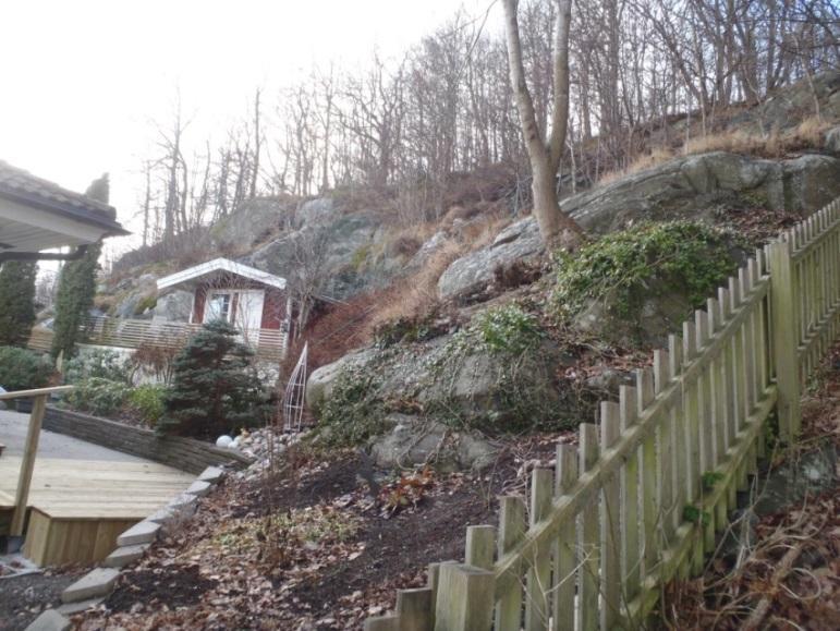 Lösa bergblock återfinns vid släntfoten ovan befintlig stenmur (Figur 2). Ett markerat slag utbildar branten strax bakom befintligt hus.