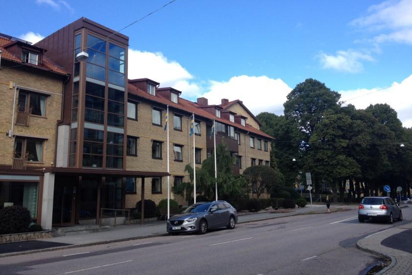 Danska vägen, vy mot Hotell Örgryte. Bebyggelsen glesas ut söderut och utmynnar i en tillfällig markparkering intill rondellen. I väster ligger Katolska skolans röda tegelbyggnader.