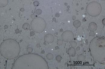 kvartskorn och järnoxider (ljusa). Oregelbundna fläckar i flera grå nyanser är hålrum. Foto från mikroskopet. R438 stick 4 Provet är taget från den största bottenslaggen (Fig. 4).