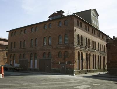 industrikaraktär med höga spröjsade fönster, tunga tegelväggar och synliga konstruktioner av stål.