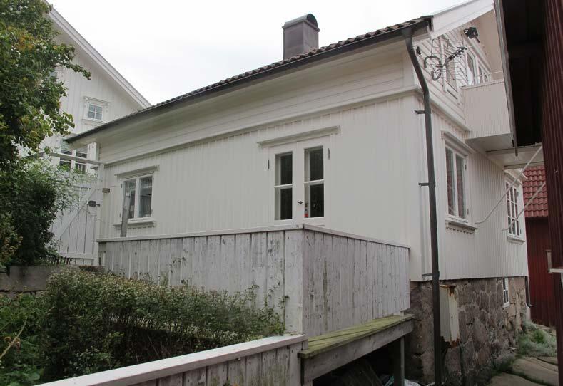 Husets västra fasad med altanen och den lilla trädgården i förgrunden.