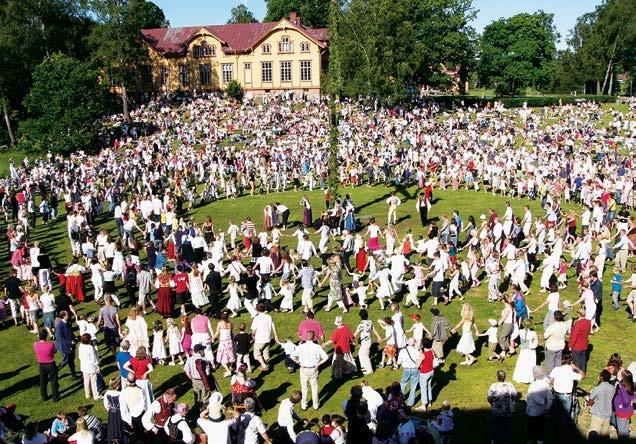 Midsommar på Nääs. Foto: Bianca Rösner och kransar av blommor. Många vuxna och barn har också kransar av blommor i håret. På midsommar brukar man äta sill, lax, färsk potatis och jordgubbar.